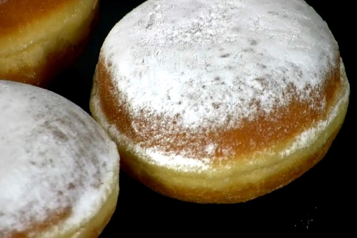 krofne posute šećerom u prahu na crnom tanjiru